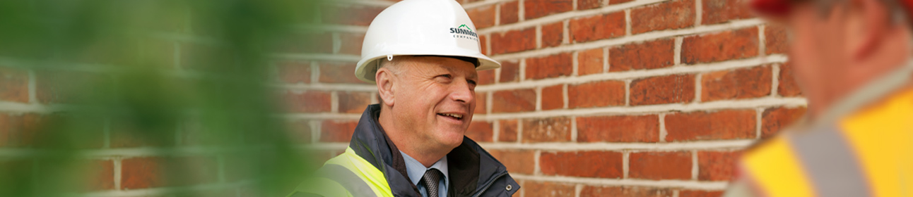 A man affiliated with Summit smiling while talking to a fellow employee