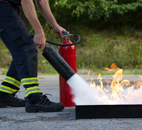 Person using fire extinguisher on flames