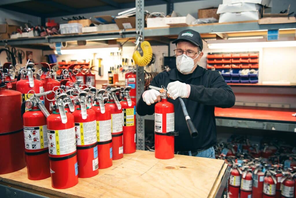 Person inspecting fire extinguishers indoors.
