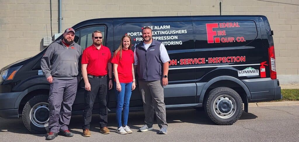Team posing in front of van.