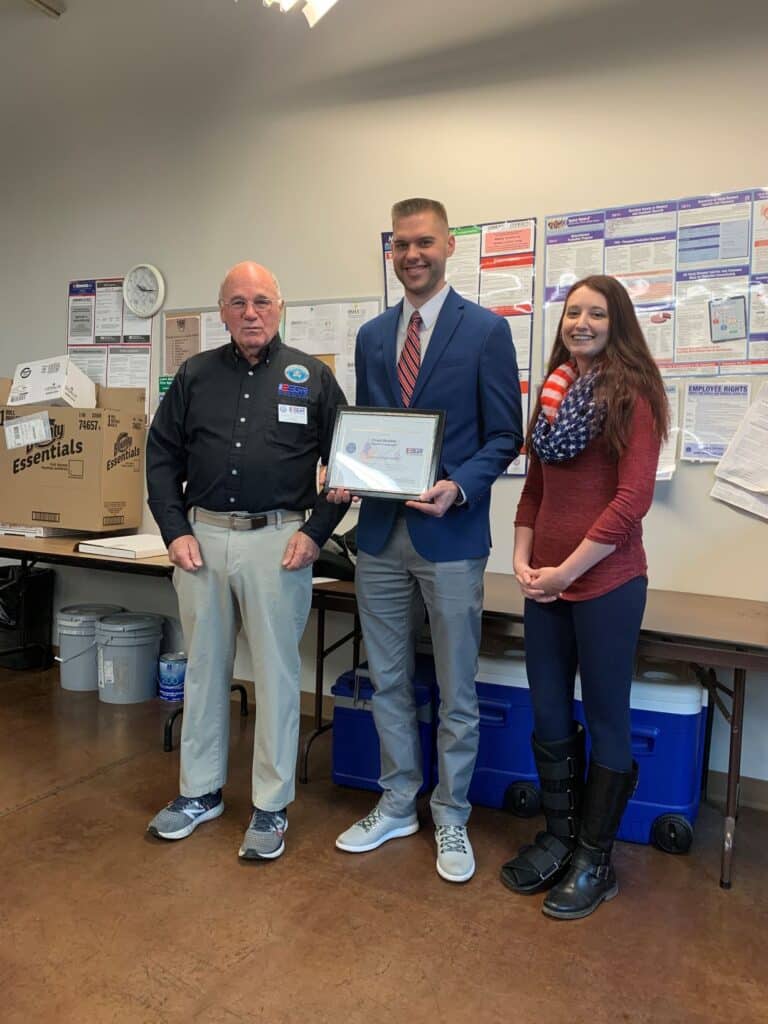 Three people with an award certificate.