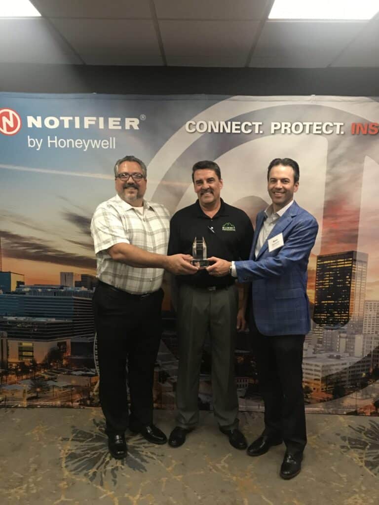 Three individuals holding an award.