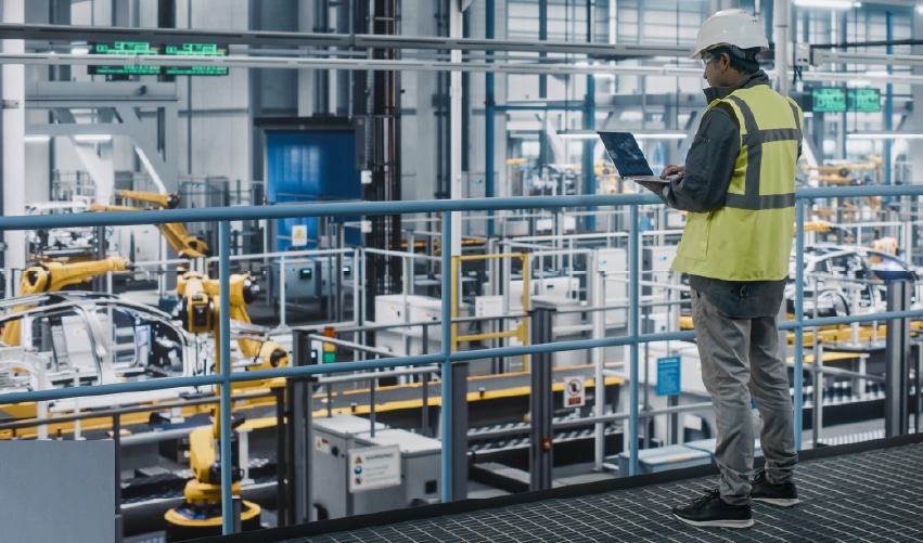Worker observing automated manufacturing process.