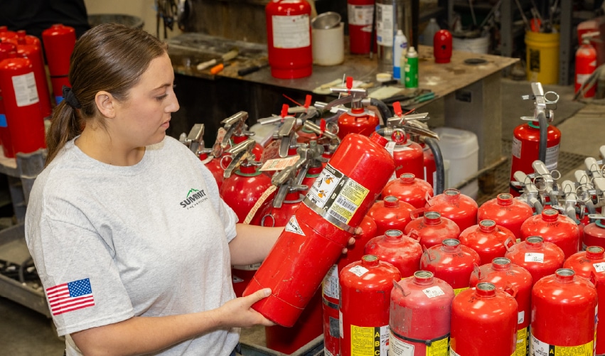 Woman holding fire extinguisher in workshop.