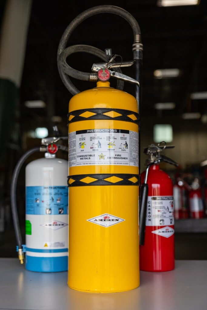 A Class D fire extinguisher in the foreground, with a carbon dioxide and water mist extinguisher in the background