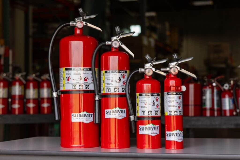 A row of four different-sized class ABC Summit Fire Protection Amerex portable fire extinguishers.