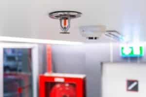 A fire sprinkler mounted in the ceiling of a commercial building