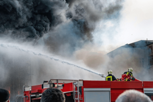 Fire fighters using a fire hose to fully extinguish a fire.